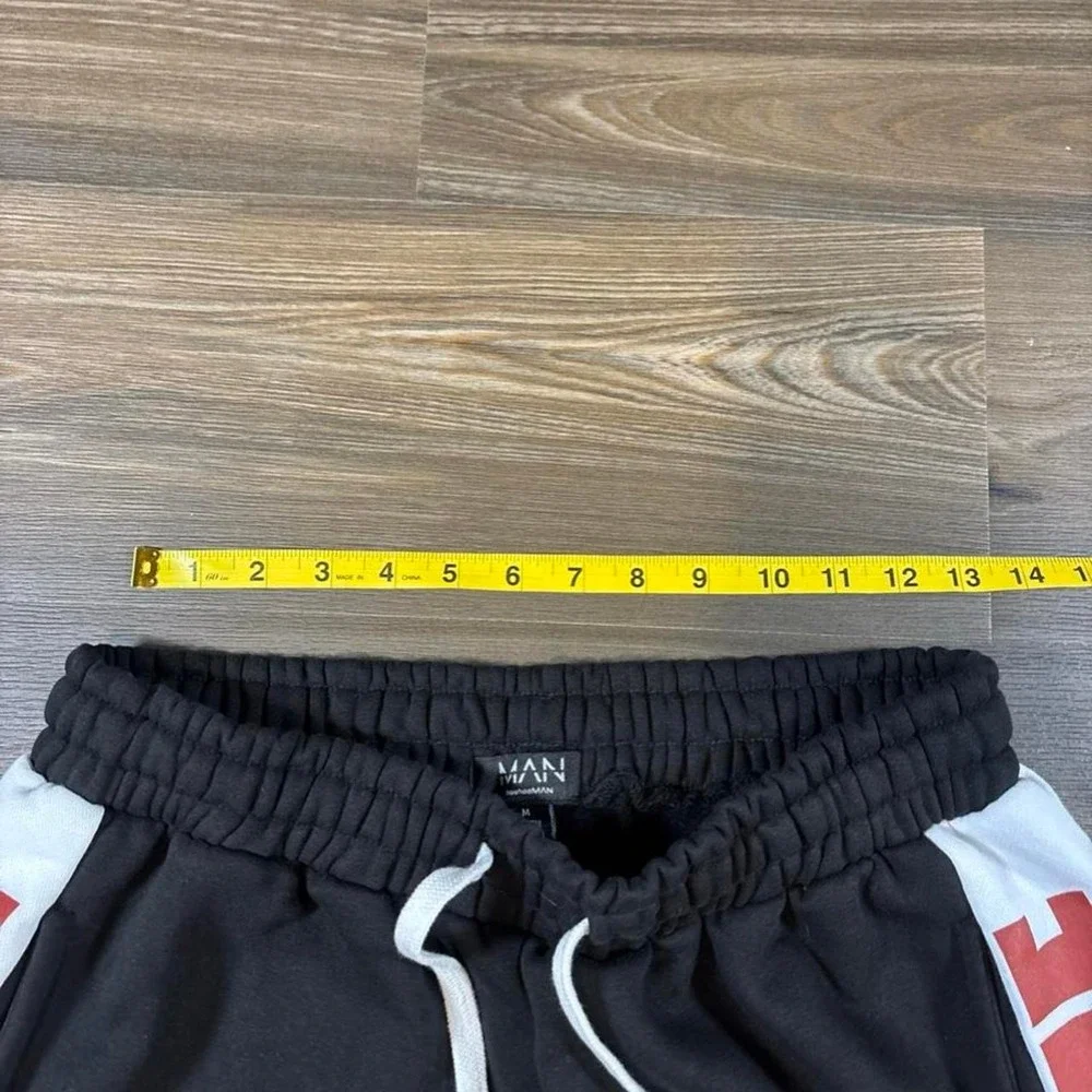 BoohooMAN black shorts with white side panels and red 'HOMME' text, size M